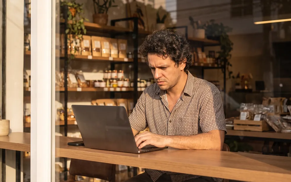 Microempreendedor trabalhando no notebook em seu próprio comércio